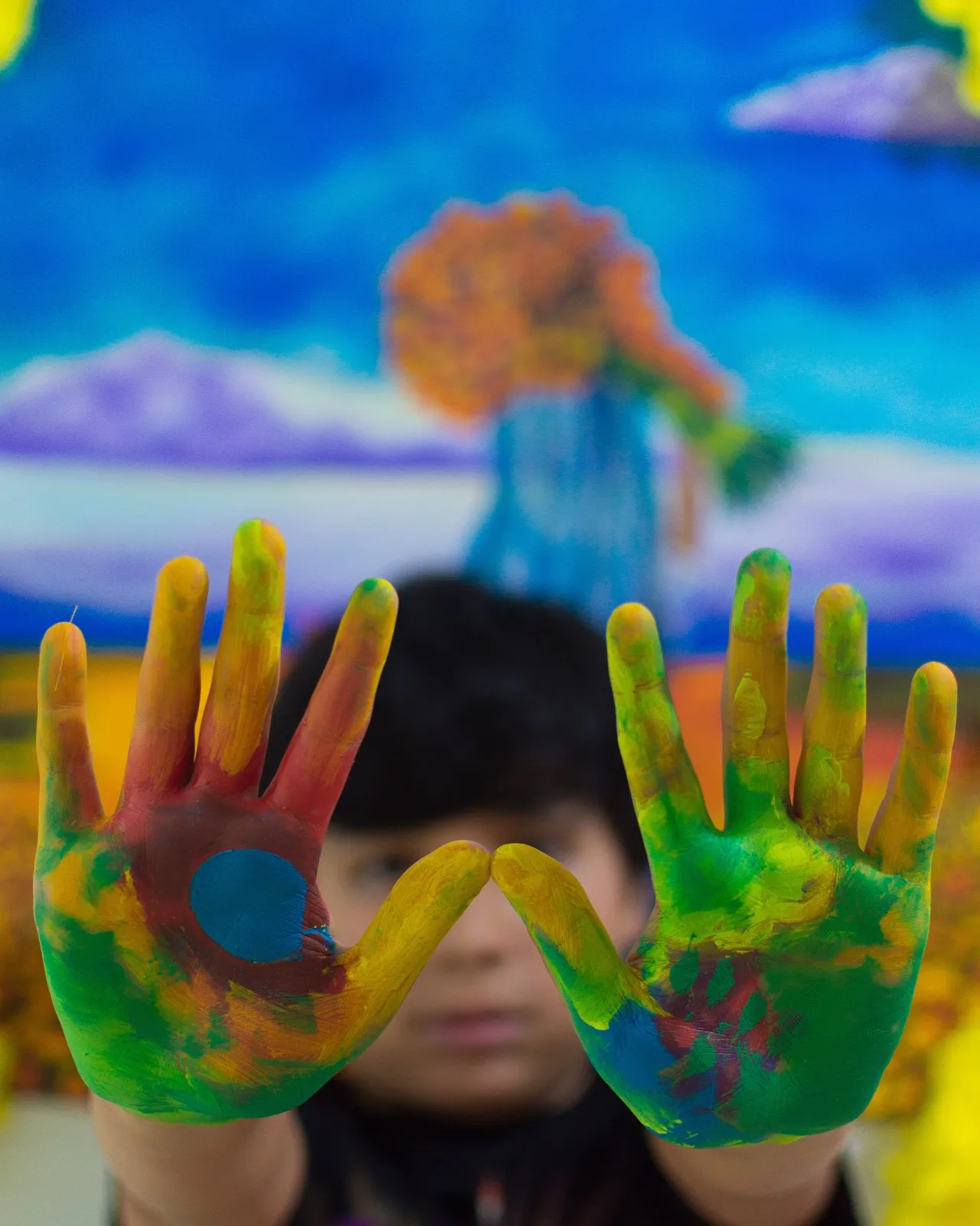 Manos cubiertas de pintura de varios colores.